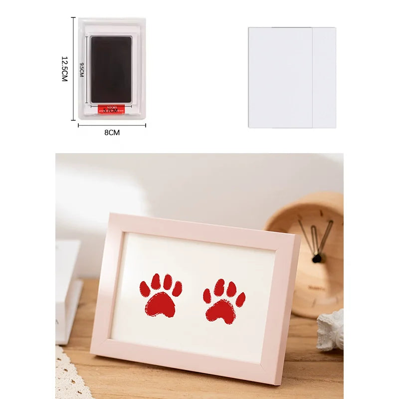 A pink wooden photo frame with a red paw print design, shown on a wooden surface.