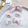 Pink bow pet hair clip with rhinestone pearl accents displayed on a white plate.