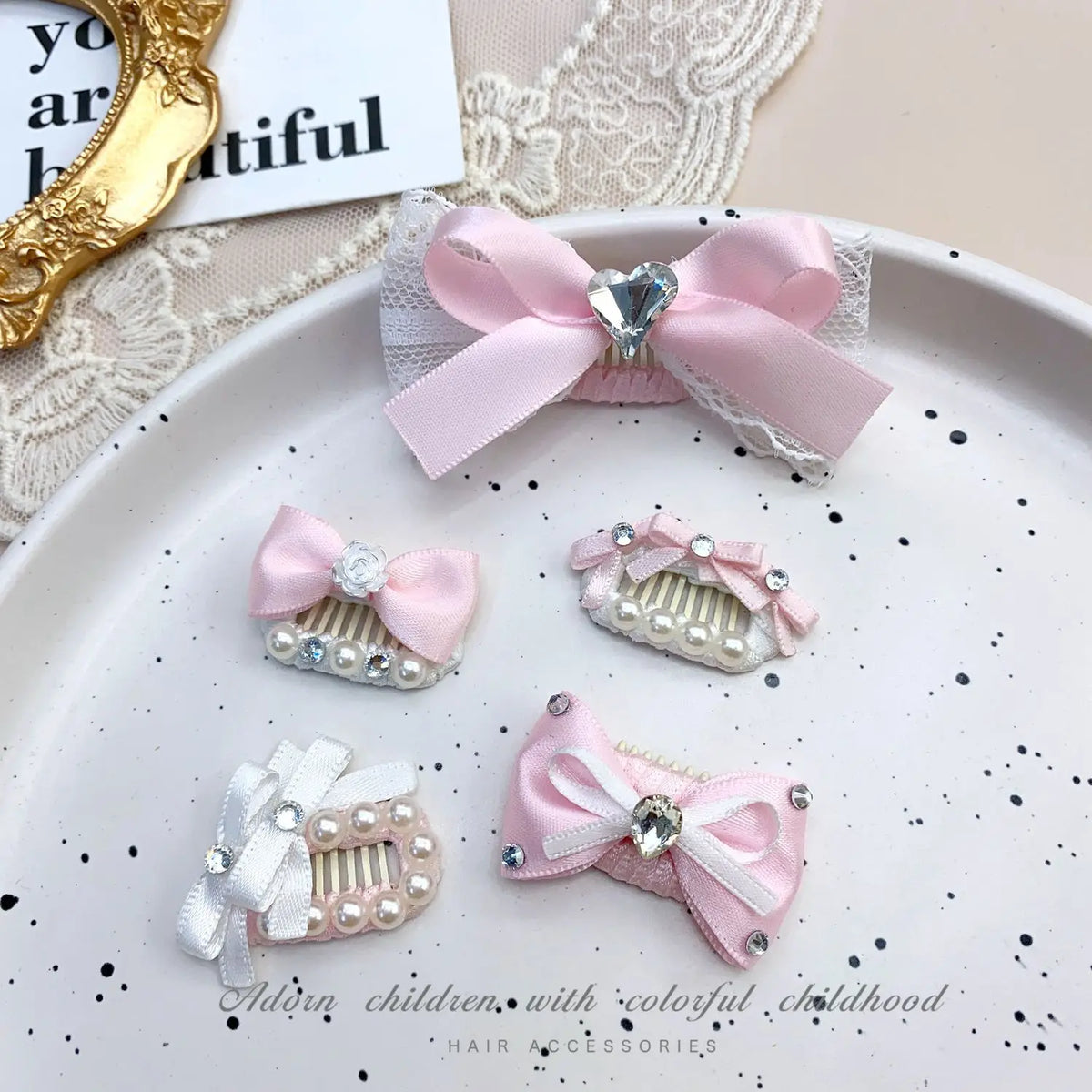 Pink bow pet hair clip with rhinestone pearl accents displayed on a white plate.