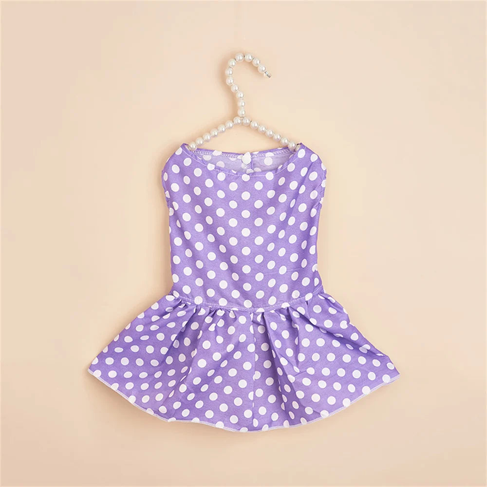 A purple polka dot dog dress for small breeds with a gathered skirt, displayed on a hanger.