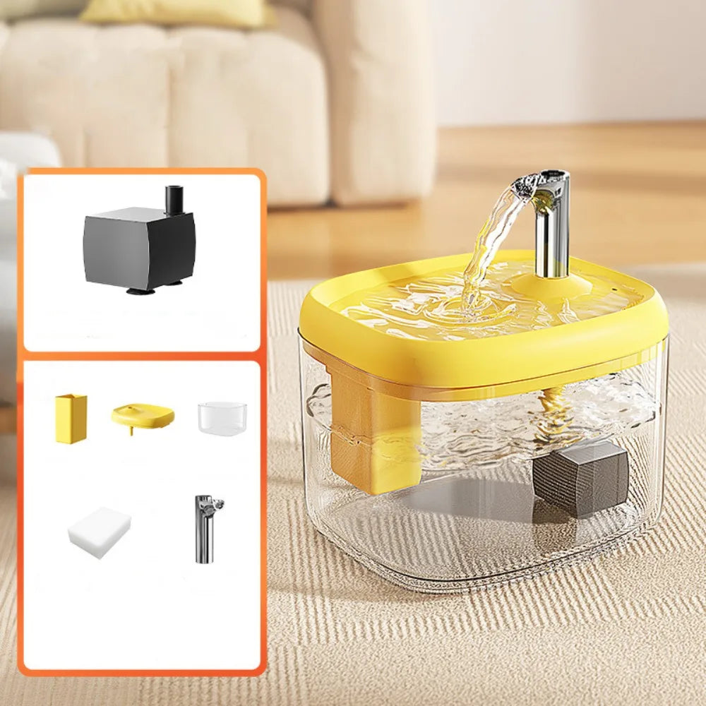 A clear glass cat drinking fountain with a yellow base and a metal spout, shown on a light-colored surface.