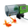 Un distributeur automatique à poisson vert et noir avec un affichage numérique, à côté d'un poisson rouge orange.