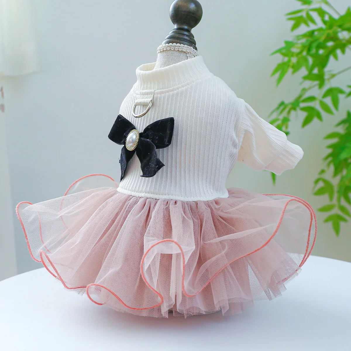 A white knit dress with a black bow detail and a pink tulle skirt displayed on a mannequin.