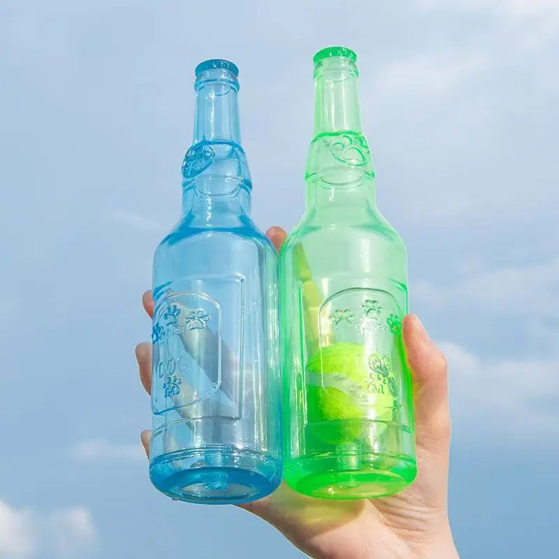 A hand holds two glass bottles of green and blue liquid, likely a dog chew toy.