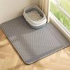 A gray waterproof double-layer cat litter mat with a removable tray is placed on a light wooden floor near a window.