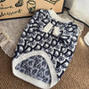 A navy and white patterned knit sweater for dogs lying on a brown textured surface.