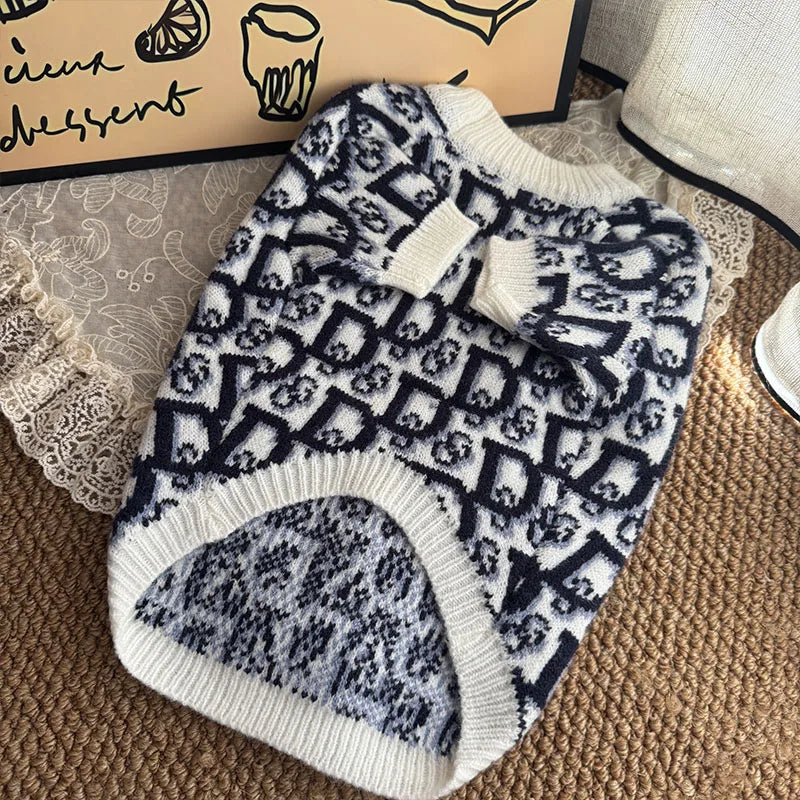 A navy and white patterned knit sweater for dogs lying on a brown textured surface.