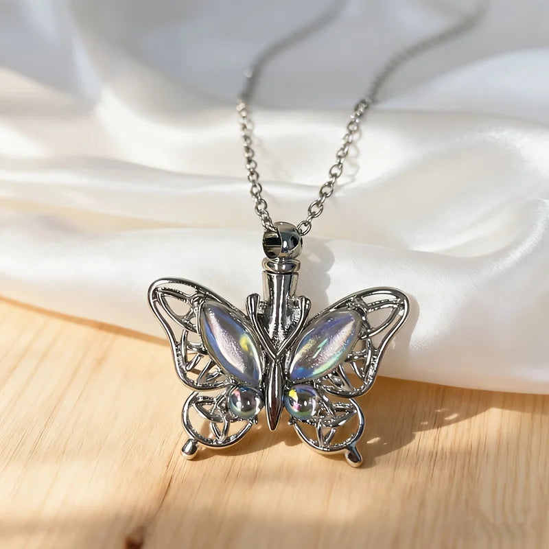 Silver butterfly ashes necklace with a detailed wing design displayed on white fabric.