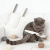 A gray cat is lying on a white surface with a white grooming comb and brush set nearby.